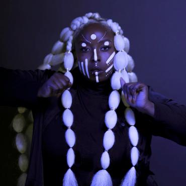 Black woman dancing with arms at her chest looking at the camera.