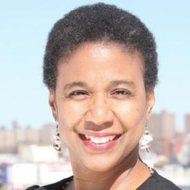 A headshot of Leslie Fields-Cruz against a city skyline in the background.