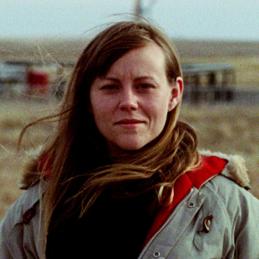 Elizabeth Chatelain, a 40-something woman filmmaker, standing in front of an oil well in North Dakota.