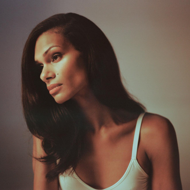 ms. z tye gazes off in a white leotard with her hair down